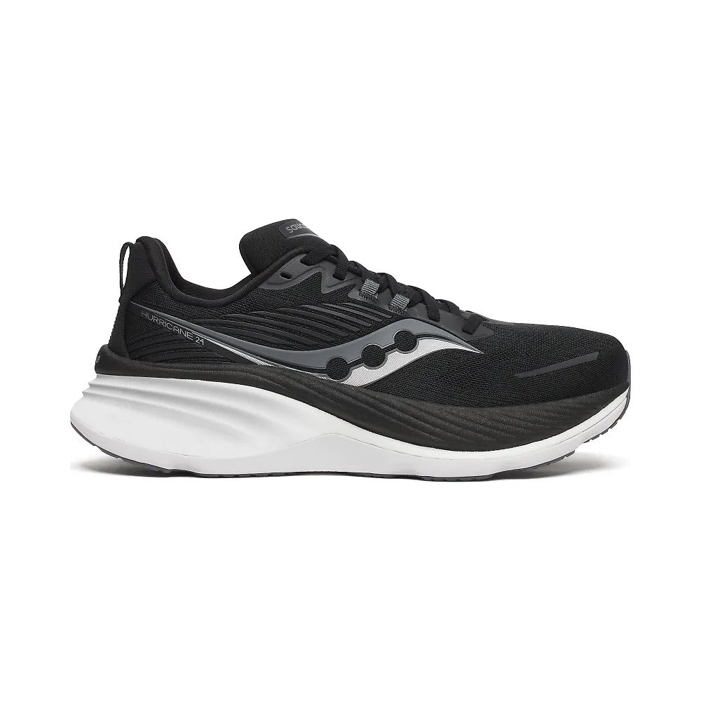 The SAUCONY HURRICANE 24 BLACK/CARBON for women is a stability running shoe from Saucony, featuring a thick sole and angular design elements. It includes dual-cushioning, a brand logo on the side, and a lace-up closure.