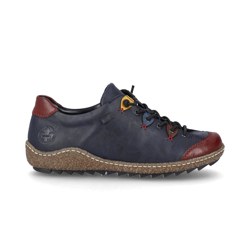 Side view of the Rieker Euro City Slip On Oxford in Navy Multi for women, featuring a dark blue leather upper with red and yellow eyelets, red accents on the toe and heel, and a textured brown rubber sole incorporating RiekerTEX technology for waterproof comfort.