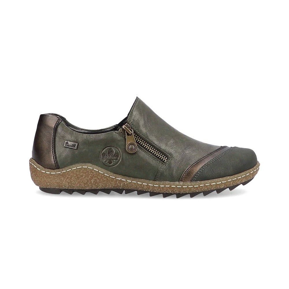 The Rieker Euro City Slip-On with Zip Olive for Women features a green and brown design, with a side zipper, stitch detailing, and a deep tread textured rubber sole for lightweight walking.