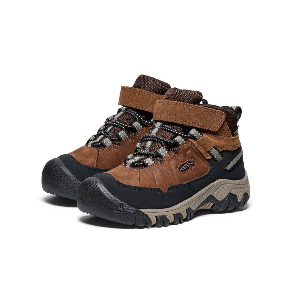 The KEEN TARGHEE IV MID WP BISON - KIDS hiker boots by Keen feature a combination of brown and black colors. They are designed for comfort and durability, with rugged soles, lace-up fronts, and velcro straps on top.