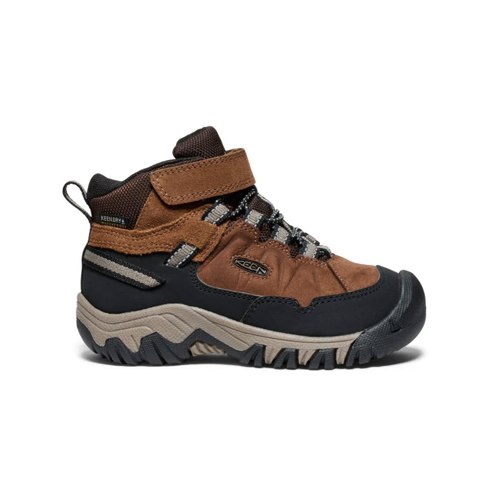 The KEEN TARGHEE IV MID WP BISON - KIDS is a brown and black hiking boot by Keen, featuring a rugged sole and Velcro strap. It is specifically designed for outdoor activities, offering durability and ensuring comfort throughout any adventure.