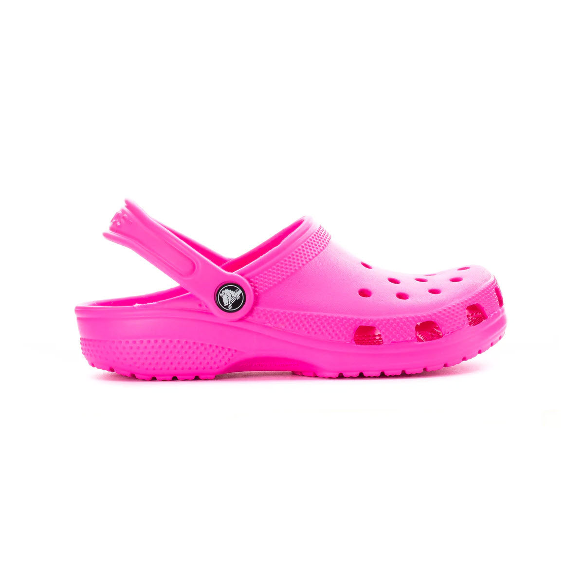 The Crocs Classic Clog Pink Crush for kids is a bright pink shoe featuring ventilation holes and an adjustable heel strap, providing ultra-comfortable wear all day.