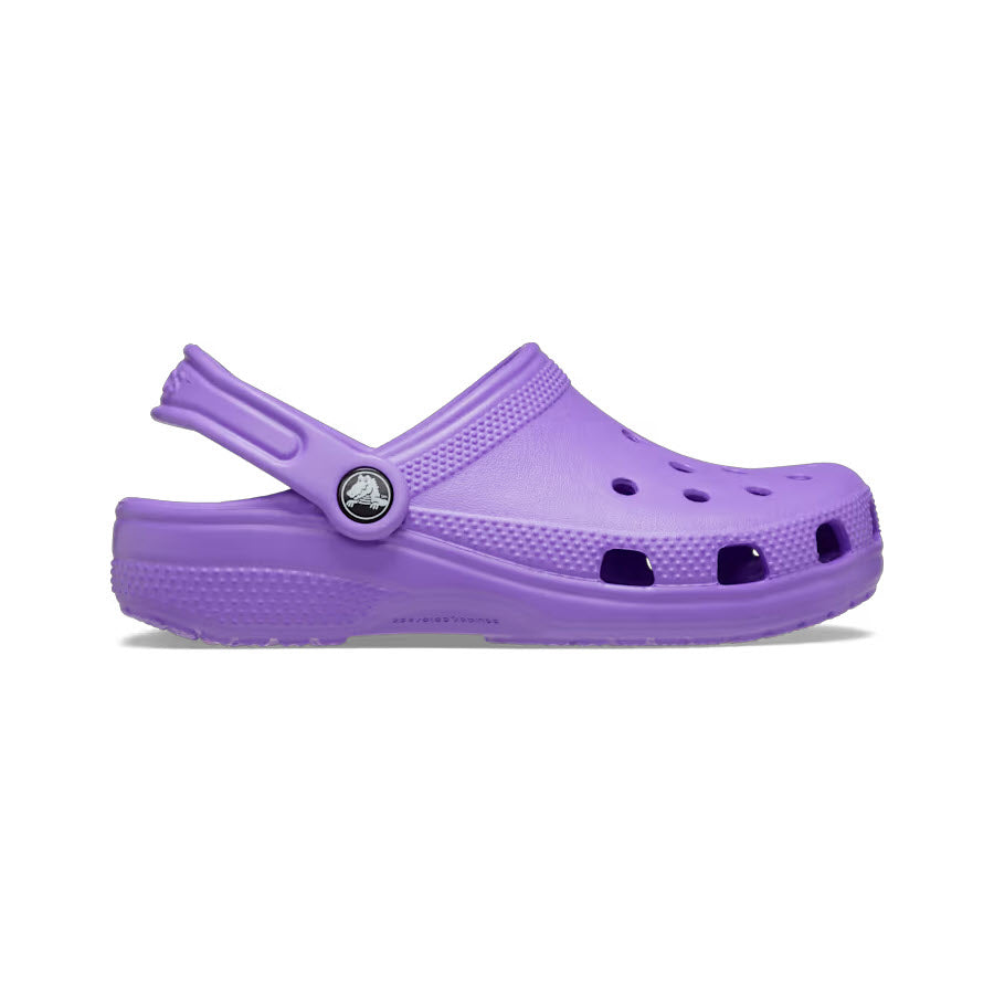 The CROCS CLASSIC CLOG GALAXY - KIDS by Crocs is a purple slip-on clog crafted from Croslite material, featuring ventilation holes, a strap at the back, and a circular logo on the side.