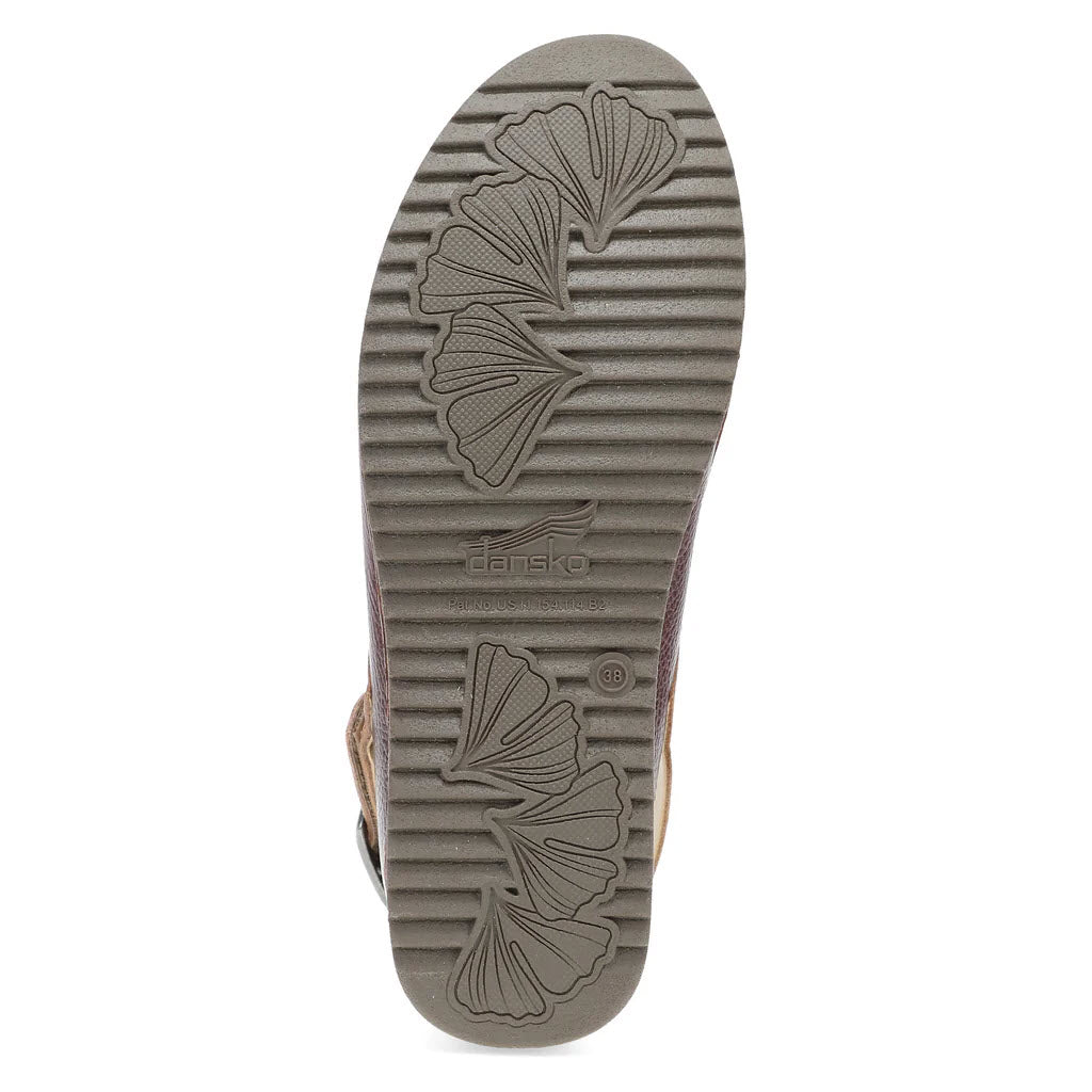 The image showcases the tread pattern on the sole of the Dansko Merrin Cordovan for women, featuring grooves and leaf-like shapes, complemented by a practical heel strap.