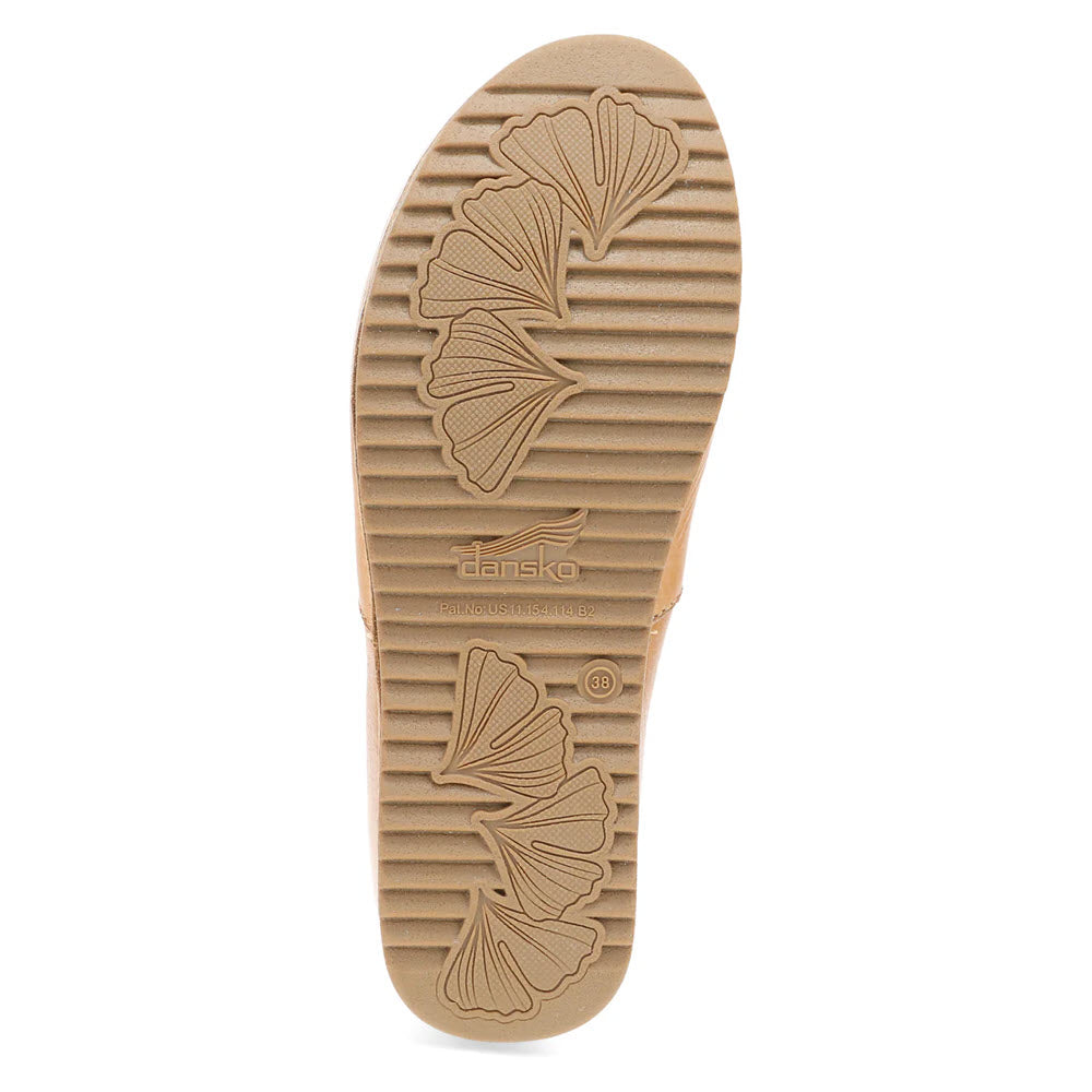 The Dansko Meara Tan - Womens shoe features a brown sole with a ribbed texture and leaf patterns on the bottom. It prominently displays the brand name &quot;Dansko&quot; and includes a size indicator of &quot;38&quot;. This casual slip-on is perfect for those who appreciate effortless style and comfort.