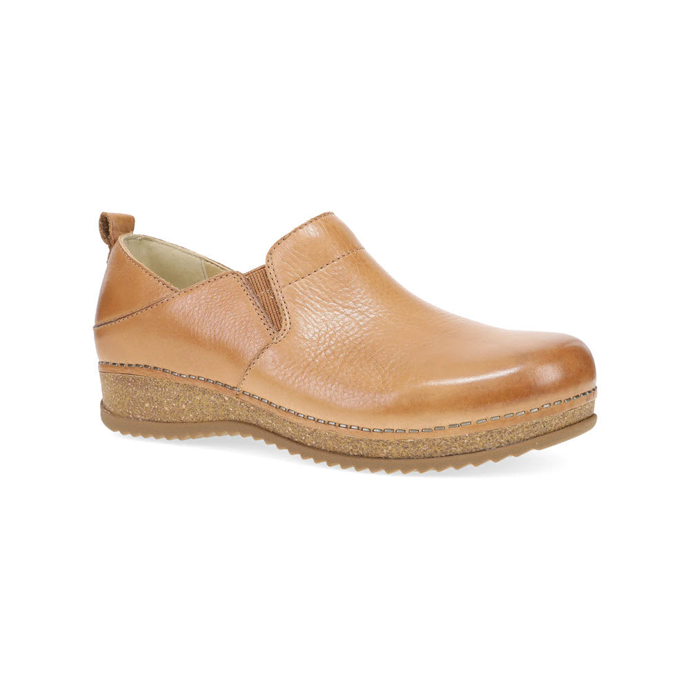 The Dansko Meara Tan - Women&#39;s shoe is a single tan slip-on featuring a slight wedge heel, textured sole, and elastic side panels for easy wear and effortless style.