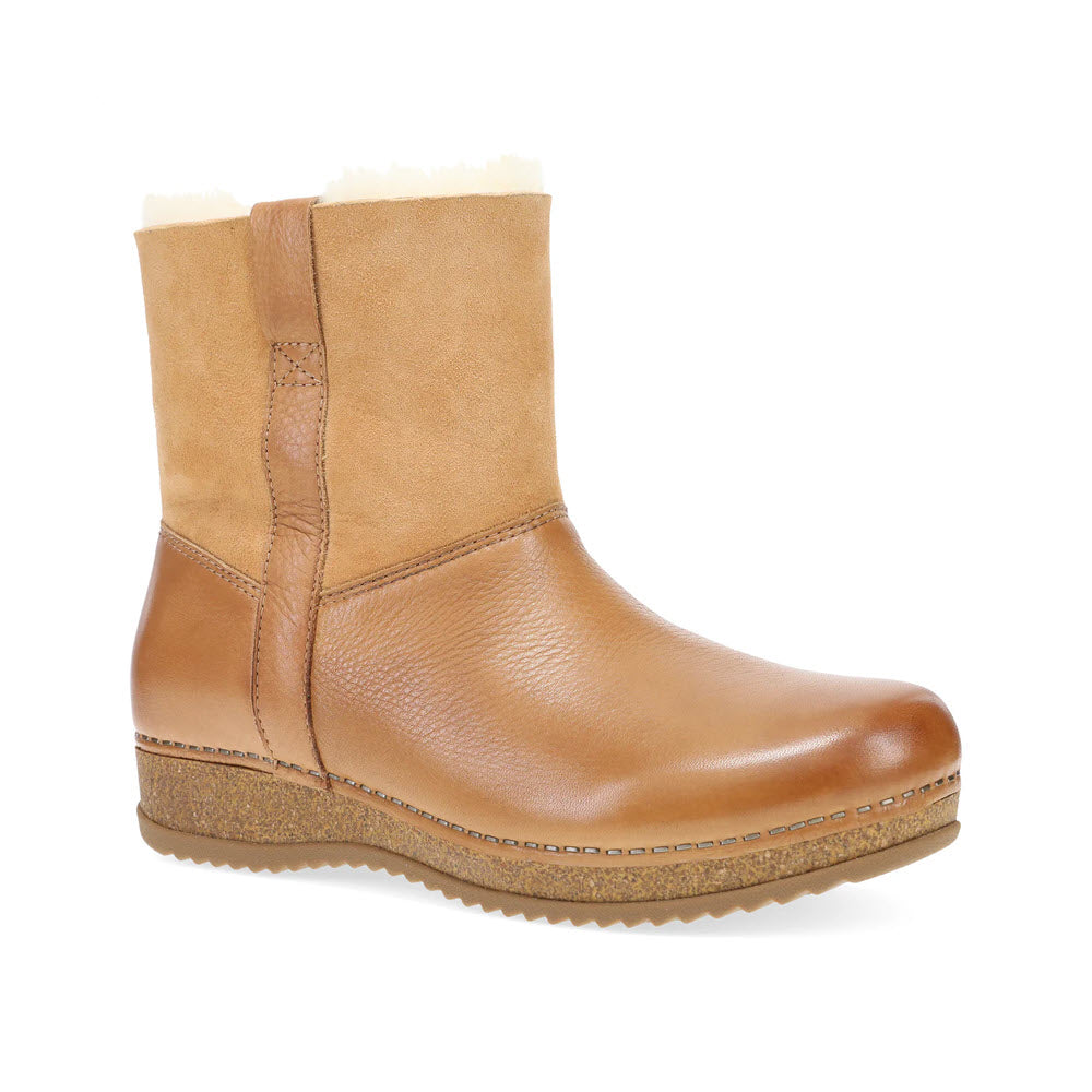 The Dansko McKenzie Tan for women is a stylish tan leather ankle boot with a rubber sole and a cozy shearling-lined interior, ideal for winter wear.