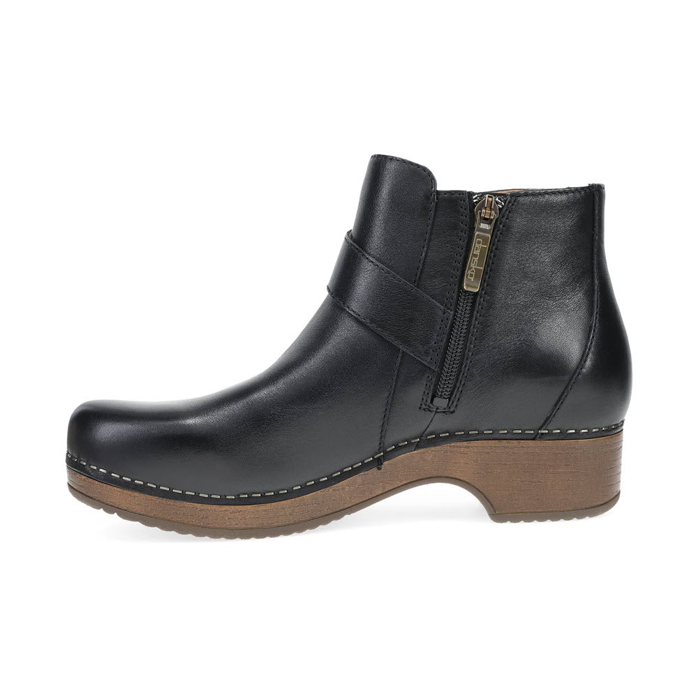 The DANSKO BRENNAN BLACK - WOMENS, a black leather ankle boot by Dansko, features a side zipper and classic rocker sole with detailed stitching on hand-selected leathers, displayed against a white background.