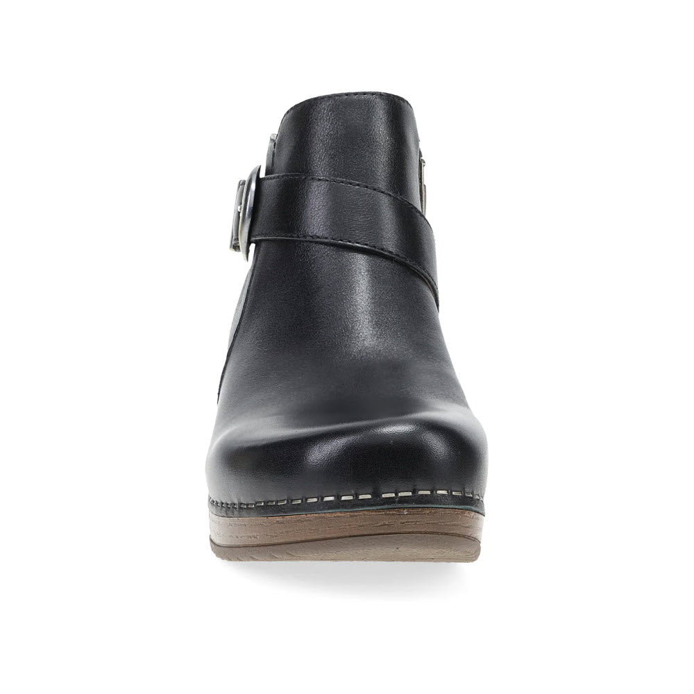 Front view of the Dansko Brennan Black ankle boot for women, featuring a side buckle, stitched sole, and slight heel. Crafted from hand-selected leathers and adorned with custom hardware for an elegant touch.