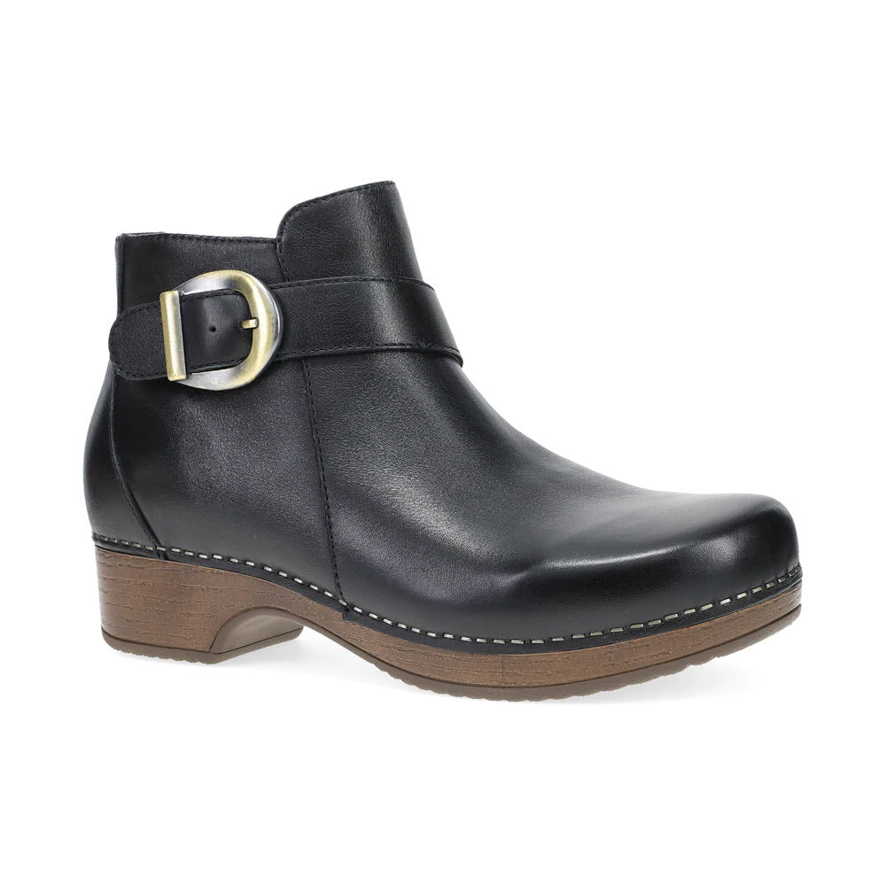 The DANSKO BRENNAN BLACK - WOMENS from Dansko is a black leather ankle boot featuring a chunky wooden heel, decorative stitching, and a large metal buckle on the side. Crafted from hand-selected leathers and adorned with custom hardware, this boot embodies timeless style and durability.