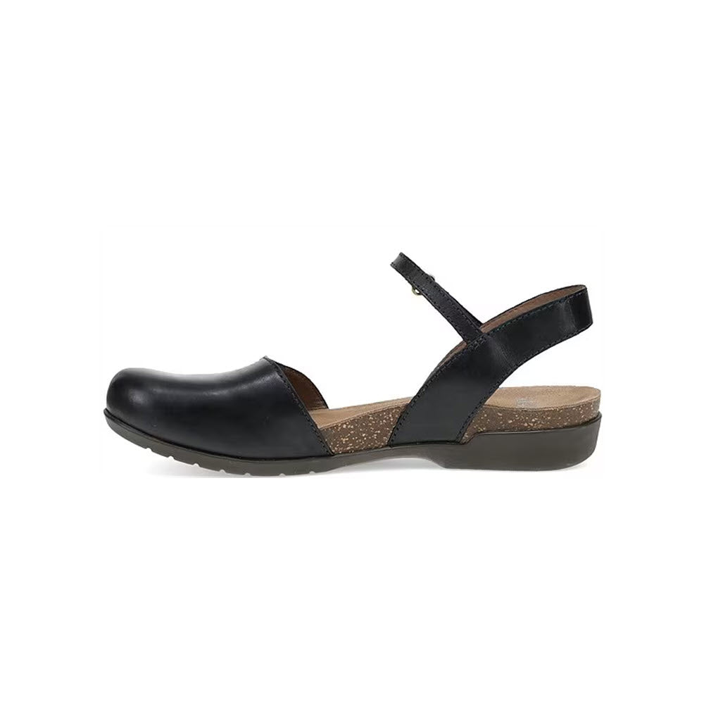 The Dansko DANSKO ROWAN BLACK LEATHER - WOMENS sandal is a black closed-toe summer sandal with a thick sole, a back strap, and an adjustable ankle strap. The shoe features leather linings, a rounded toe, and a textured beige insole for added comfort.