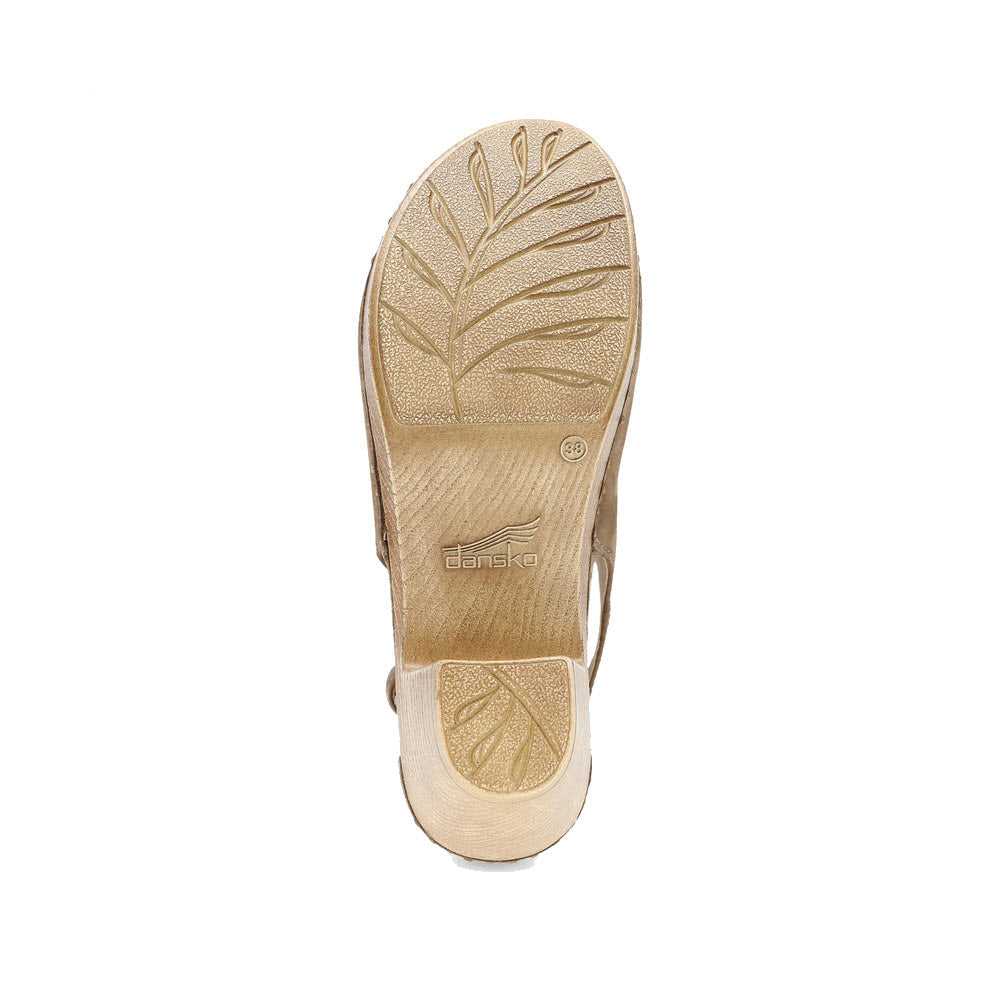 The image showcases the sole of a beige DANSKO SASSY MOREL - WOMENS shoe, featuring a leaf pattern design and &quot;Dansko&quot; prominently printed at the center. With contoured arch support and high-quality leather craftsmanship, this shoe offers both style and comfort.