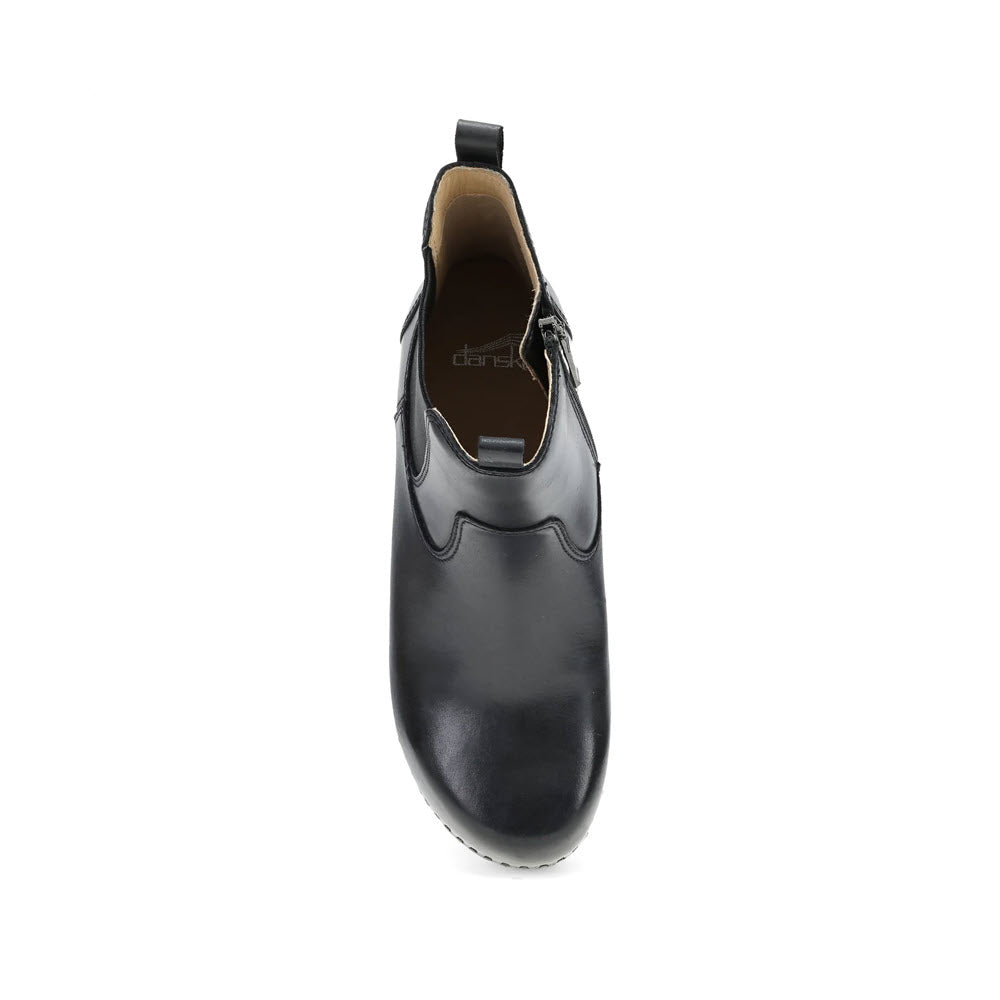 A top view of the Dansko Shayna Black women&#39;s slip-on shoe, featuring black leather, a ridged sole, and a wrist loop at the back, perfect for making a subtle fashion statement.