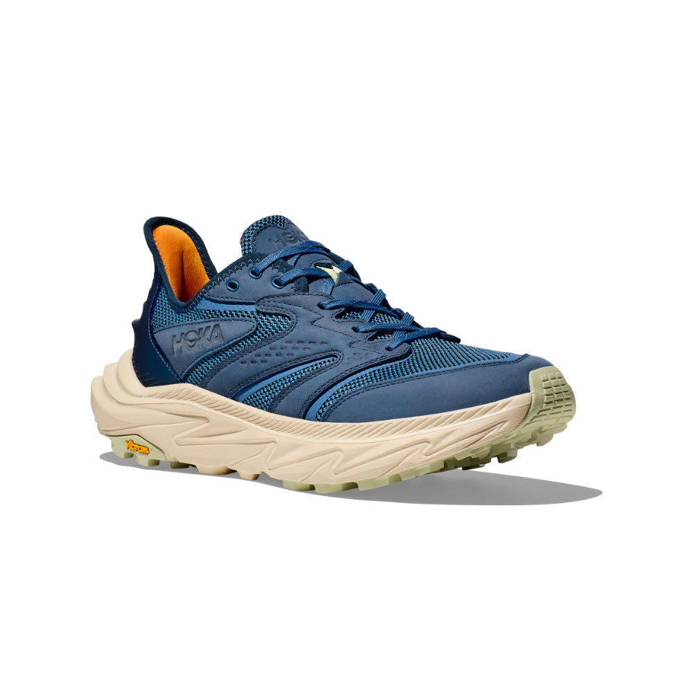 The HOKA ANACAPA 2 FREEDOM Foggy Night/Oat Milk - Mens is a blue athletic shoe with a beige sole, featuring a mesh upper, lace-up front, and branded side logo. It is designed with the innovative Hoka geometry for enhanced comfort and stability.