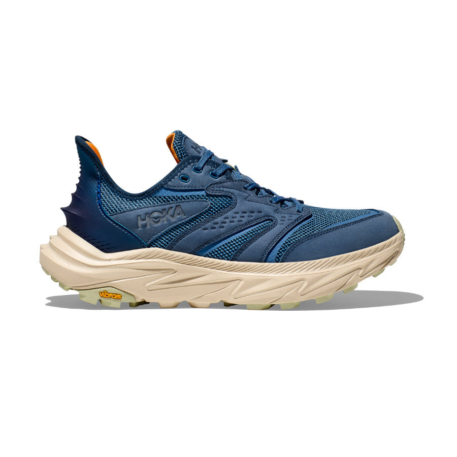 The HOKA ANACAPA 2 FREEDOM FOGGY NIGHT/OAT MILK - MENS by Hoka is a blue athletic shoe with beige soles, featuring mesh fabric panels and orange accents, designed with HOKA geometry.