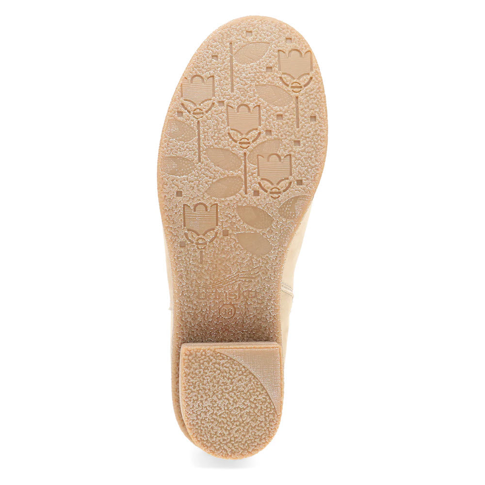 A view of the sole of the Dansko Daisie Sand women&#39;s beige waterproof Chelsea boot, showcasing an embossed pattern of leaves and flower motifs across the bottom surface.