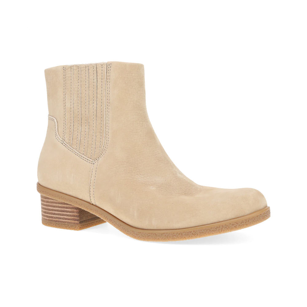 The DANSKO DAISIE SAND - WOMENS is a beige ankle boot featuring a low stacked heel, signature Dansko support, and visible stitching details on the side panel.