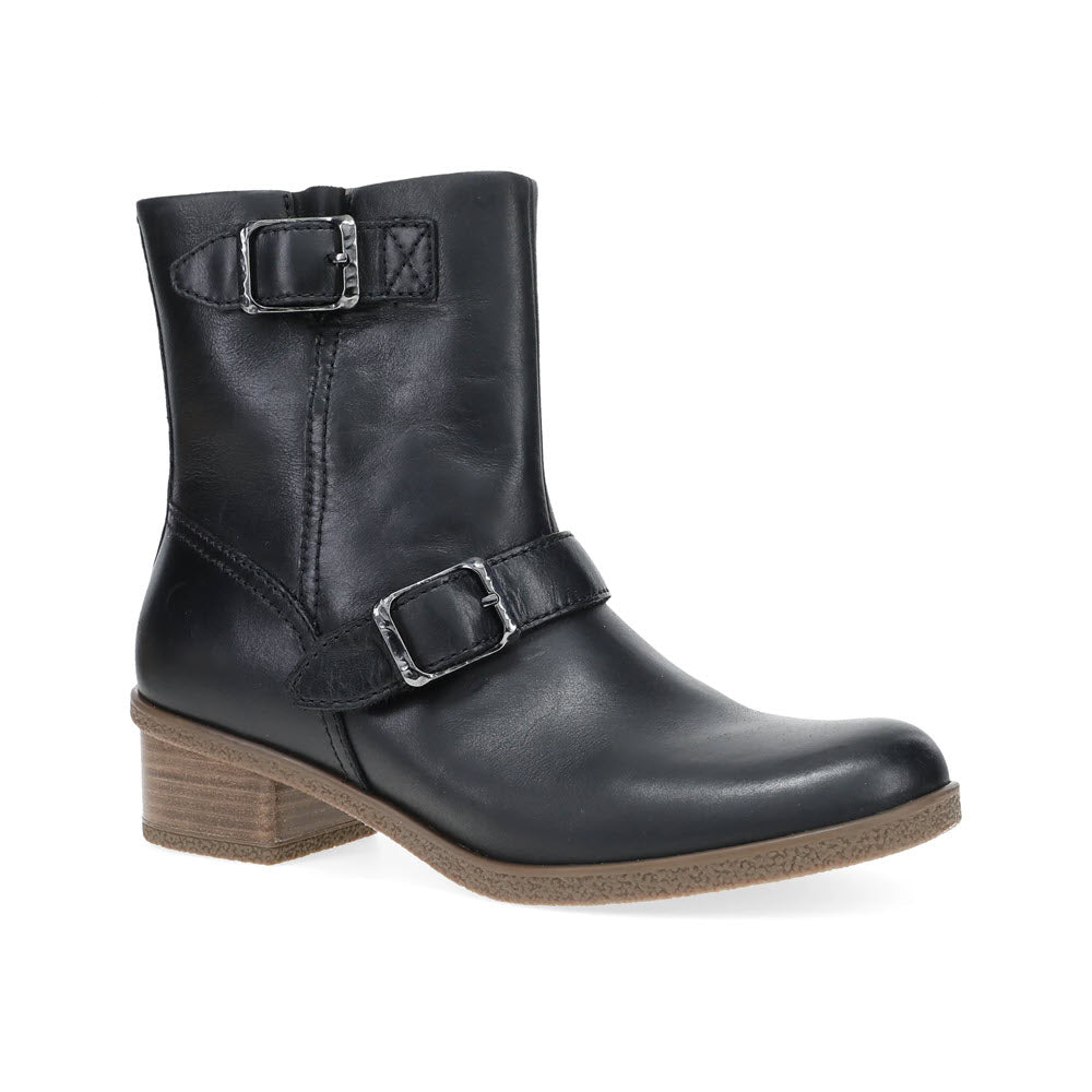 The Dansko Delphine Black for women features a sleek black leather moto bootie design with two silver buckles, a wooden block heel, and stylish hardware details, shown from a side view.