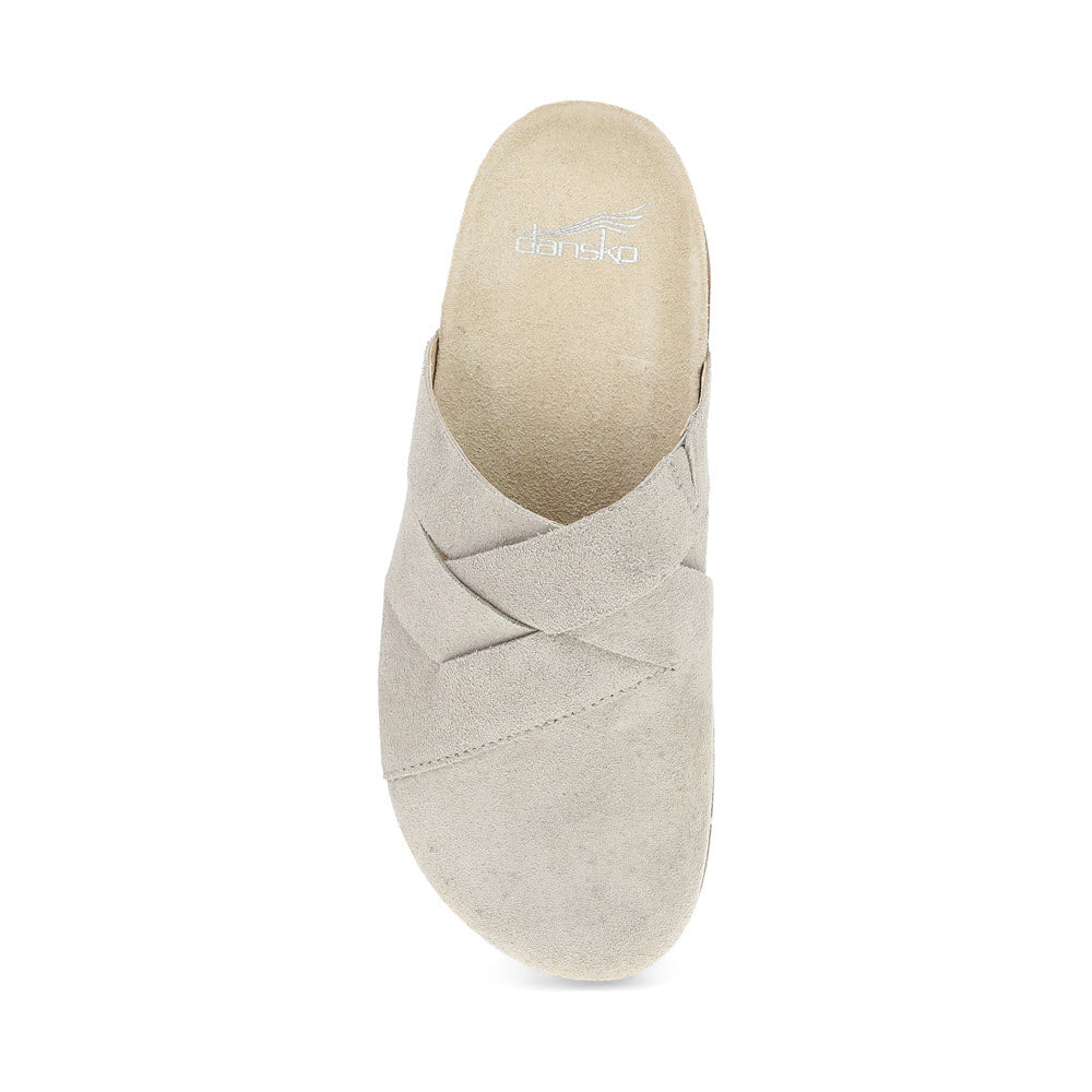 The Dansko Daniella Taupe for women is a single light beige mule with suede uppers that features a crisscross design and an open back. The brand name &quot;Dansko&quot; is visible on the insole, complemented by its comfortable cork-based sole.