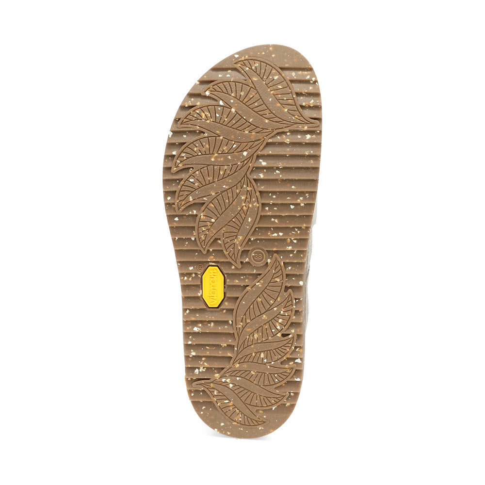 Bottom view of a single shoe sole, featuring leaf patterns and a yellow Dansko branded emblem. The suede upper of the DANSKO DANIELLA TAUPE - WOMENS complements the brown, speckled sole, adding to its rustic appeal.