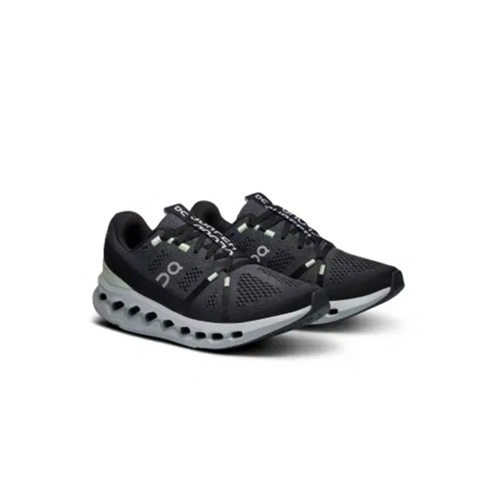 A pair of On Running Cloudsurfer Iron/Glacier women&#39;s athletic sneakers with black and gray tones, white soles, featuring the &quot;On&quot; logo on the sides and a ventilated design, incorporating CloudTec cushioning for ultimate comfort.