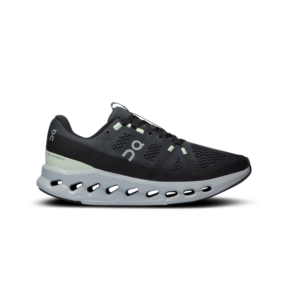 Introducing the ON RUNNING CLOUDSURFER IRON/GLACIER - WOMENS from On Running: a sophisticated black and grey athletic sneaker accented with white and green highlights. This innovative shoe features a unique sole design with oval cutouts and CloudTec cushioning, promising an unparalleled running experience.