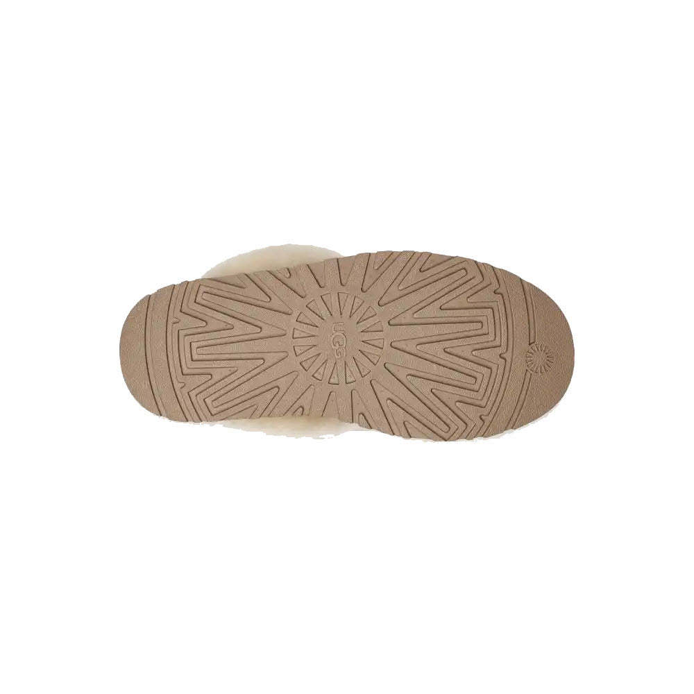 Bottom view of the UGG Disquette Chestnut sole showcases its beige color with intricate geometric and circular patterns, enhancing traction. The slip-on silhouette offers both convenience and style, making it perfect for any casual outing.