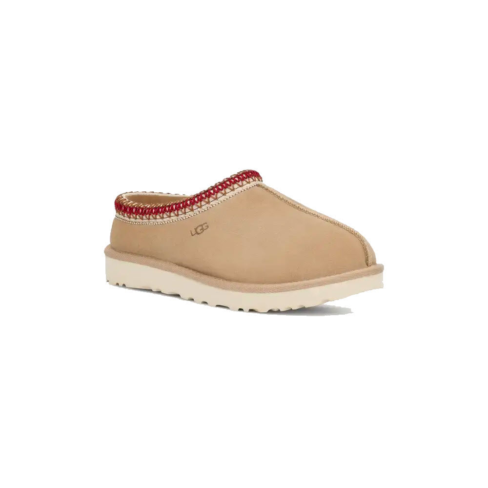 Introducing the UGG TASMAN SAND/DARK CHERRY for Women, featuring tan suede with a white sole and dark cherry trim around the opening. The Ugg logo is prominently displayed on the side. This ultra-lightweight slipper boasts a timeless design that guarantees comfort with every step.