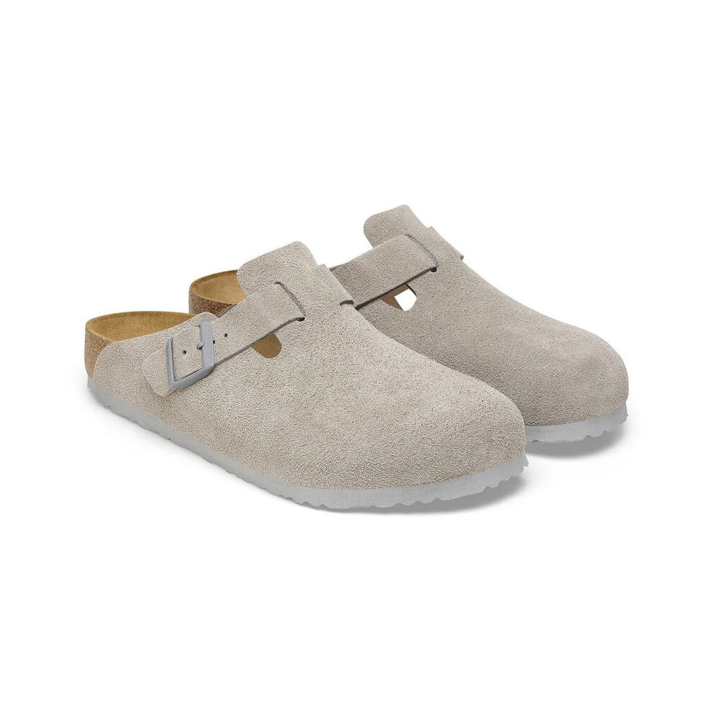 A pair of Birkenstock Boston Stone Coin clogs for women in gray suede featuring buckle straps, contoured cork footbeds, and rubber outsoles.