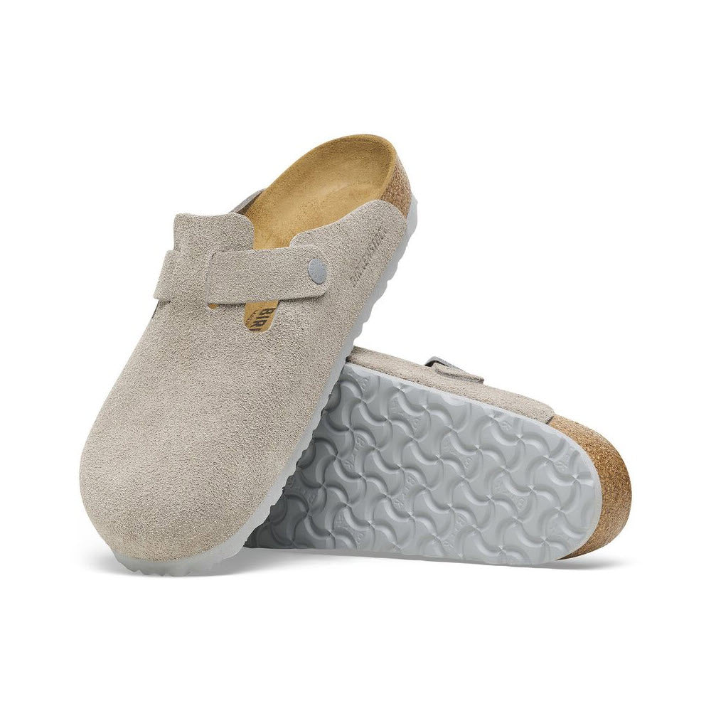 A pair of BIRKENSTOCK BOSTON STONE COIN - WOMENS clogs by Birkenstock, featuring beige suede uppers, cork footbeds, and white patterned rubber soles.