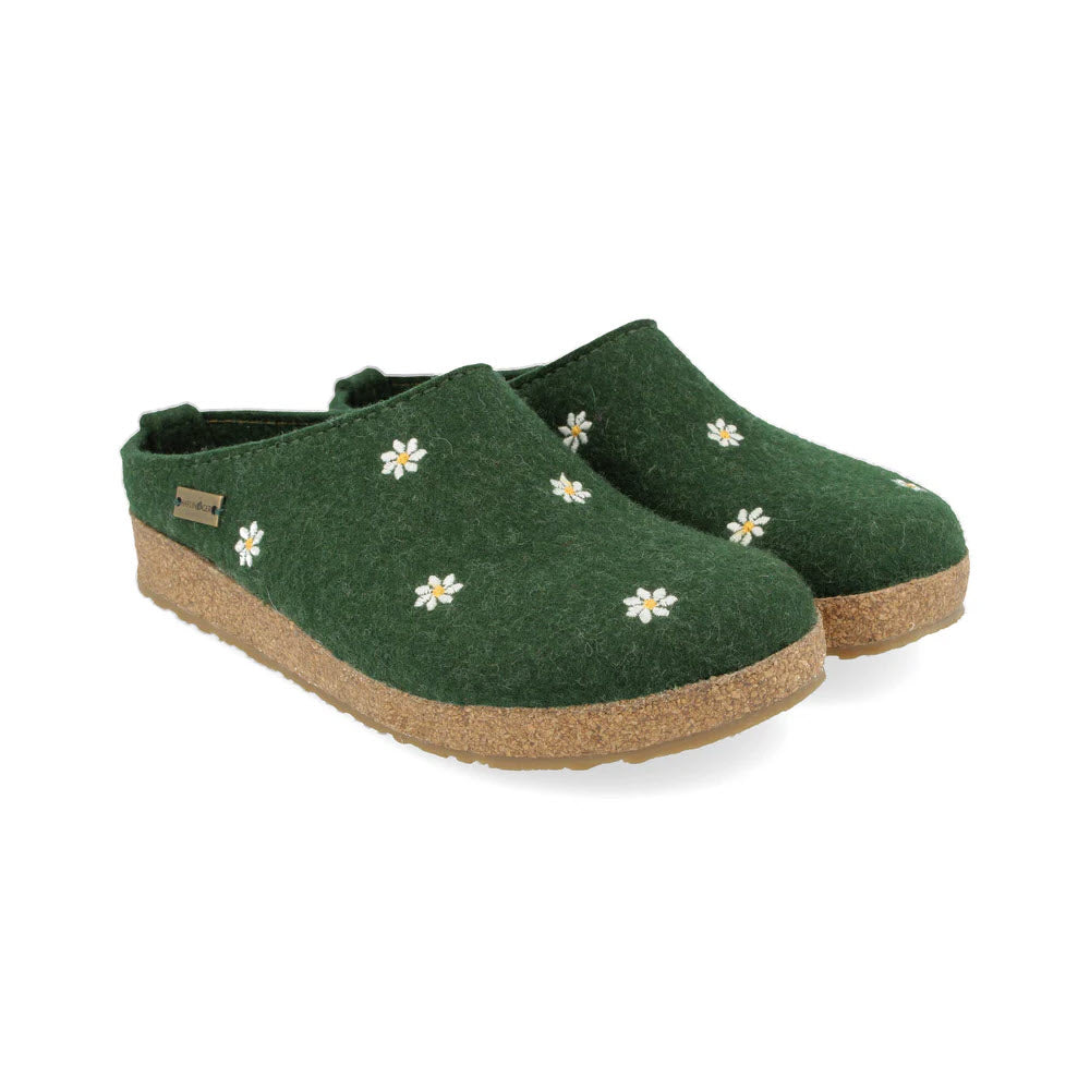 Discover the comfort of Haflinger MARGHERITA GREEN - WOMENS clogs by Haflingers, crafted from snug wool felt. These stylish green clogs are adorned with delicate white floral embroidery and rest on supportive cork soles, offering an ideal balance of style and comfort.