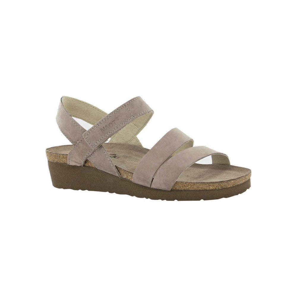 Beige **NAOT KAYLA STONE - WOMENS** with a low wedge heel featuring three stylish straps over the top and an adjustable ankle strap for added comfort. The sole appears to be made of cork. **Brand Name: Naot**