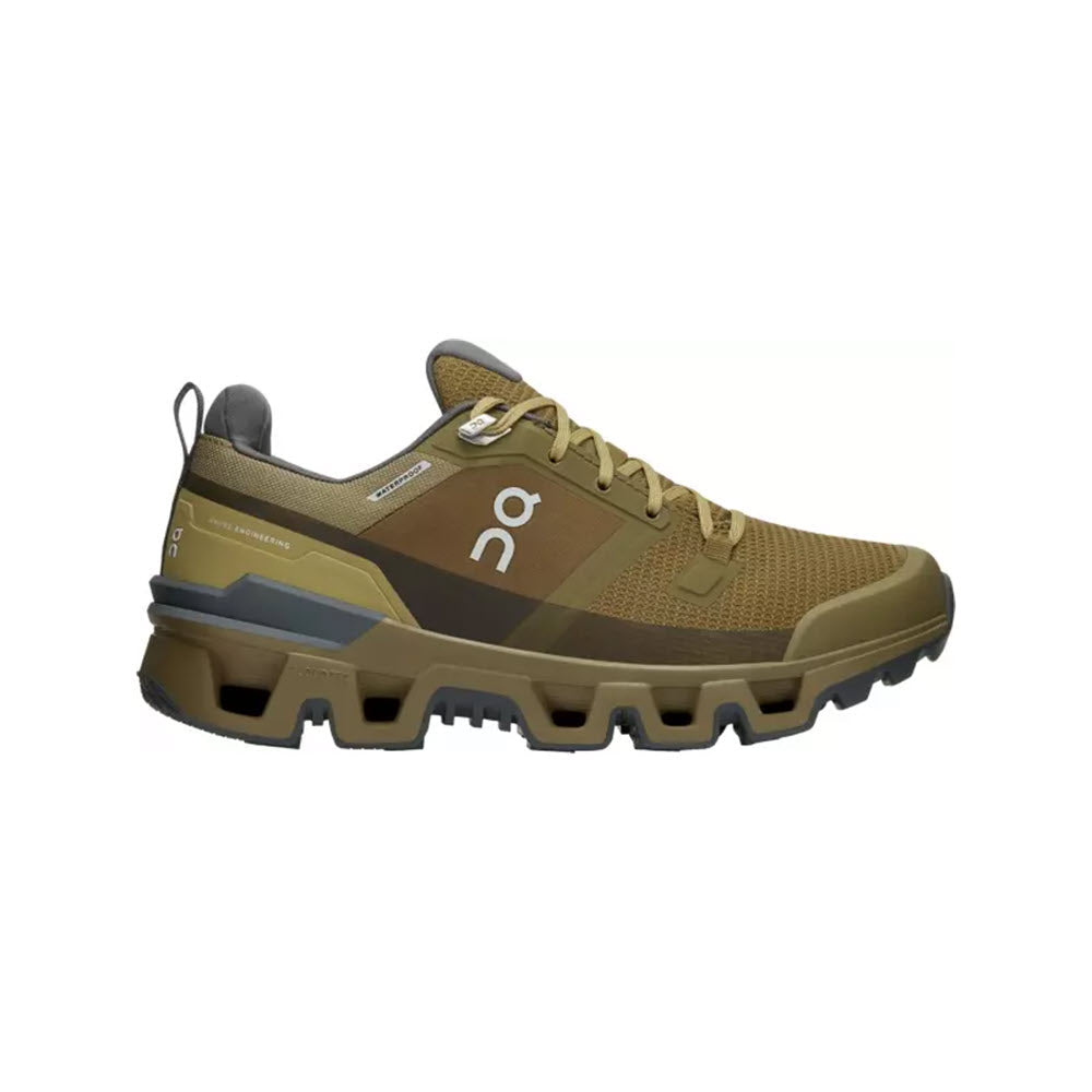 Introducing the On Running ON CLOUDWANDER WATERPROOF HUNTER/SAFARI - WOMENS, a lightweight athletic shoe featuring a brown and green mesh upper, distinctive sole design, and &quot;On&quot; branding on the side. Perfect for outdoor performance.