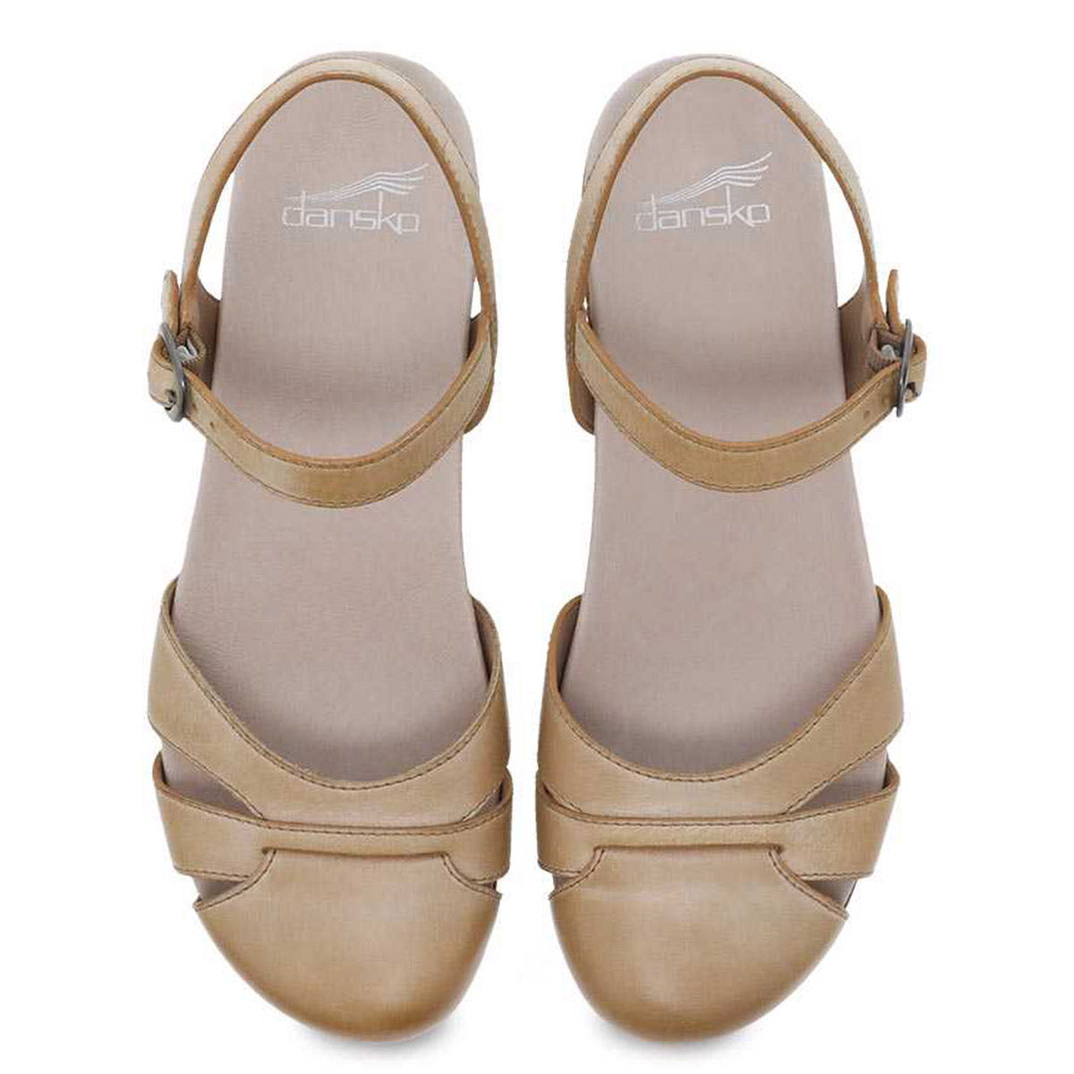 A pair of beige Dansko Betsey Tan Milled Burnished clogs with memory foam cushioning, displayed against a white background.
